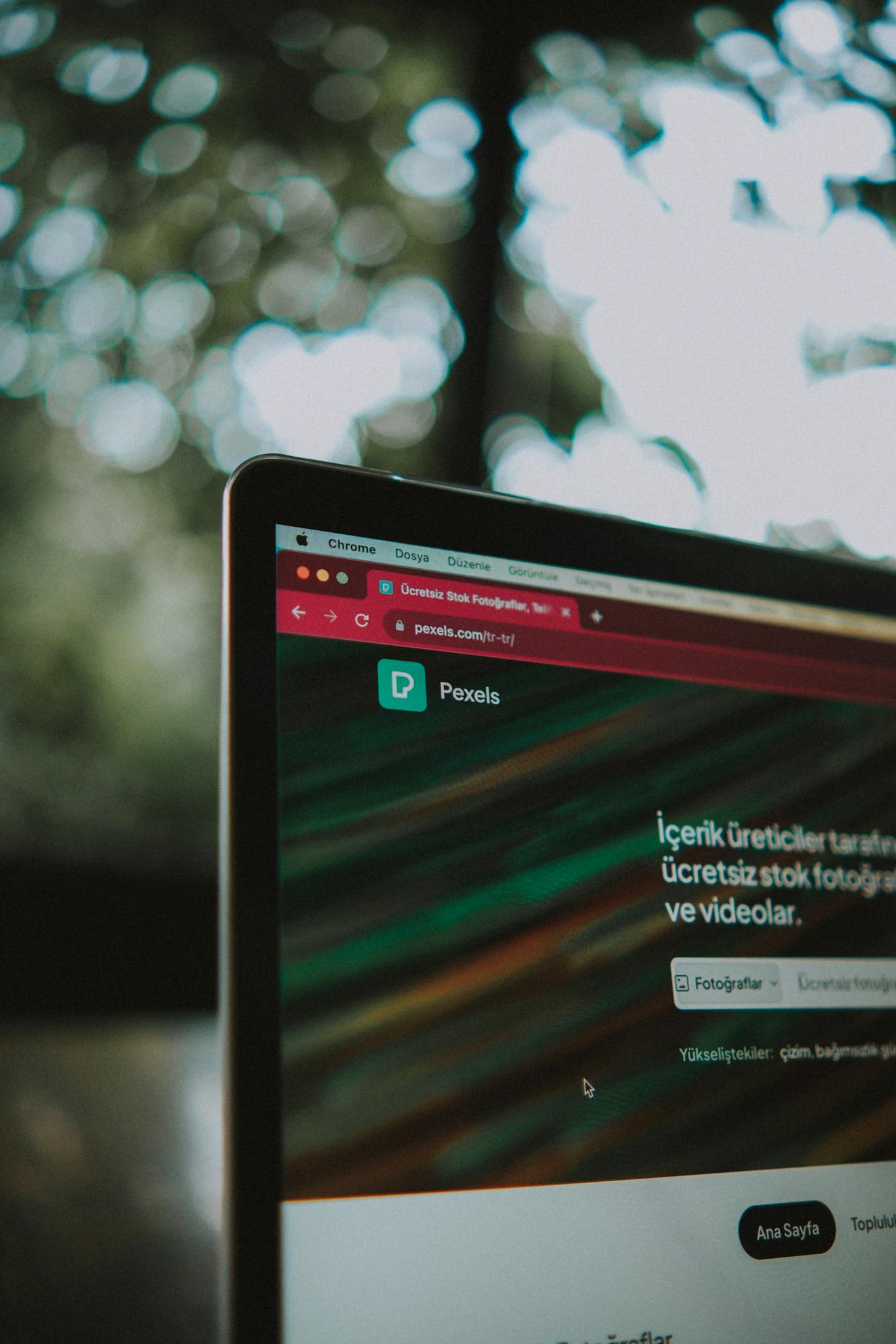 Close-up of a laptop screen with the Pexels website open, showcasing a vibrant bokeh background.